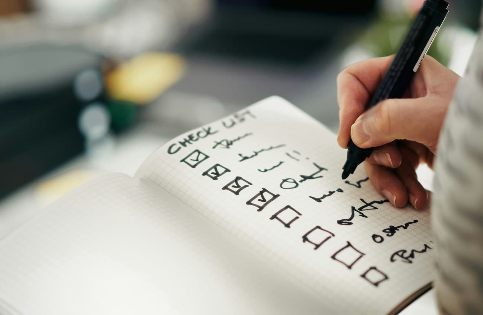 Hand ticking items off a handwritten checklist in a notebook